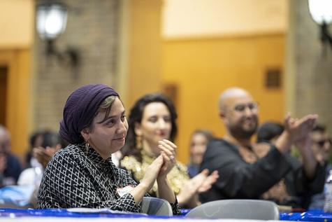 Eine Frau mit Kopftuch applaudiert bei einer Veranstaltung 