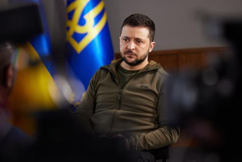 Pr&auml;sident Selenskyj auf einer Pressekonferenz: Man sieht ihn durch eine L&uuml;cke zwischen den Kameras. Er wirkt traurig und ernst.