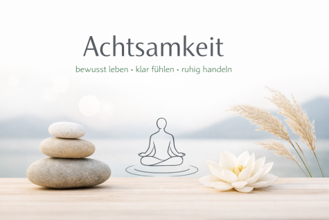 Steine &uuml;bereinander gestapelt auf einem Holztisch, daneben eine Lotusblume und dekorative Halme. Text betont Achtsamkeit.