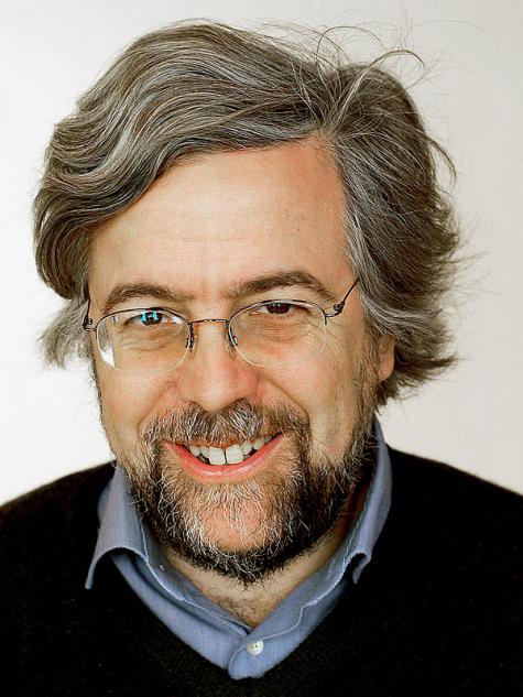 Andreas Gross (2007) - Ein l&auml;chelnder Mann mit grauen Haaren, Brille und Bart, tr&auml;gt ein schwarzes Kleidungsst&uuml;ck &uuml;ber einem blauen Hemd.