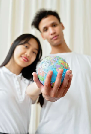 Zwei junge Menschen halten einen Globus in der Hand, l&auml;chelnd mit einem verschwommenen Hintergrund.