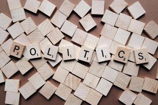 Beigefarbene h&ouml;lzerne Scrabble-Buchstaben buchstabieren das Wort Politik auf vielen anderen leeren quadratischen St&uuml;cken