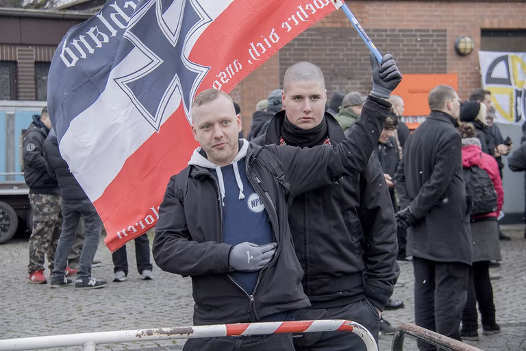 Zwei Neonazis auf einer Demo mit einer rechten Flagge