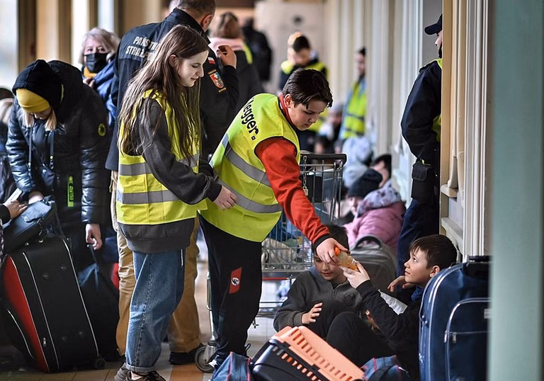 Zwei Freiwillige Helfer versorgen Gefl&uuml;chtete in einem Bahnhof