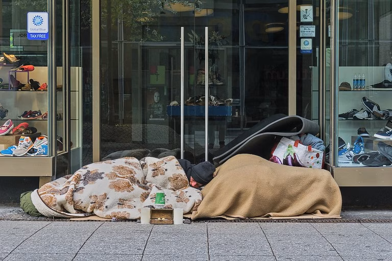 Ein Mann schl&auml;ft vor einem Gesch&auml;ft