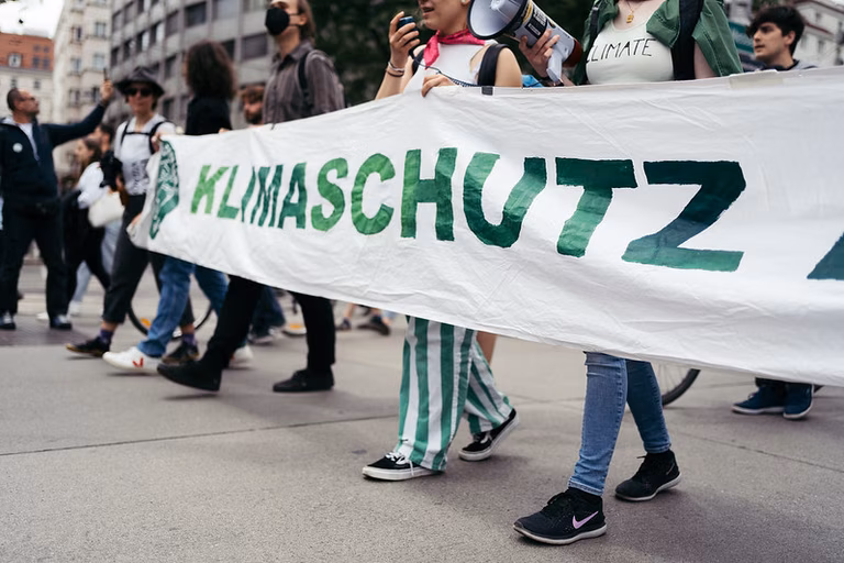 Ein Demozug mit einem Banner auf dem Klimaschutz steht