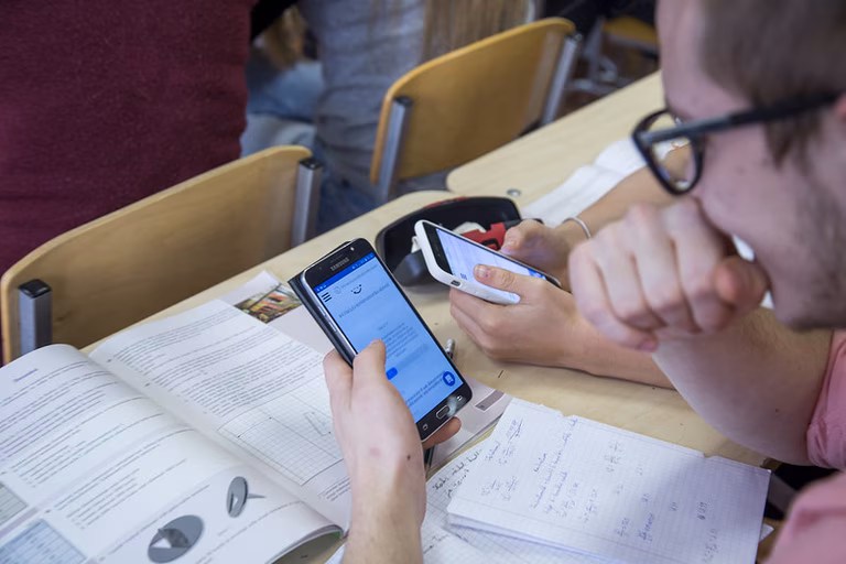 Zwei Menschen mit Smartphones im Unterricht